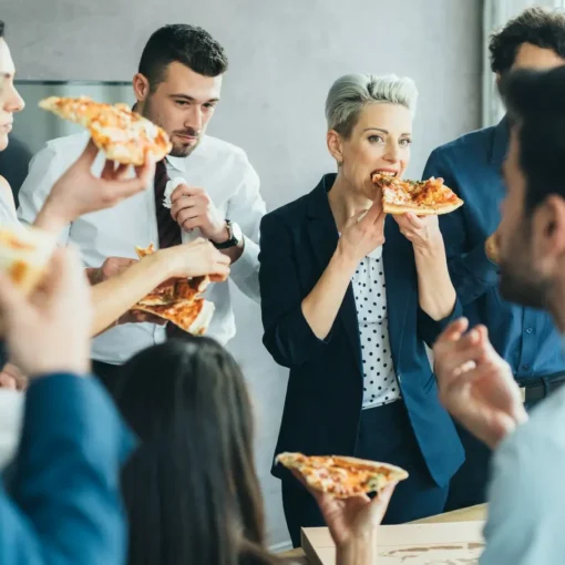 pracownicy na spotkaniu biznesowym jedzą pizzę